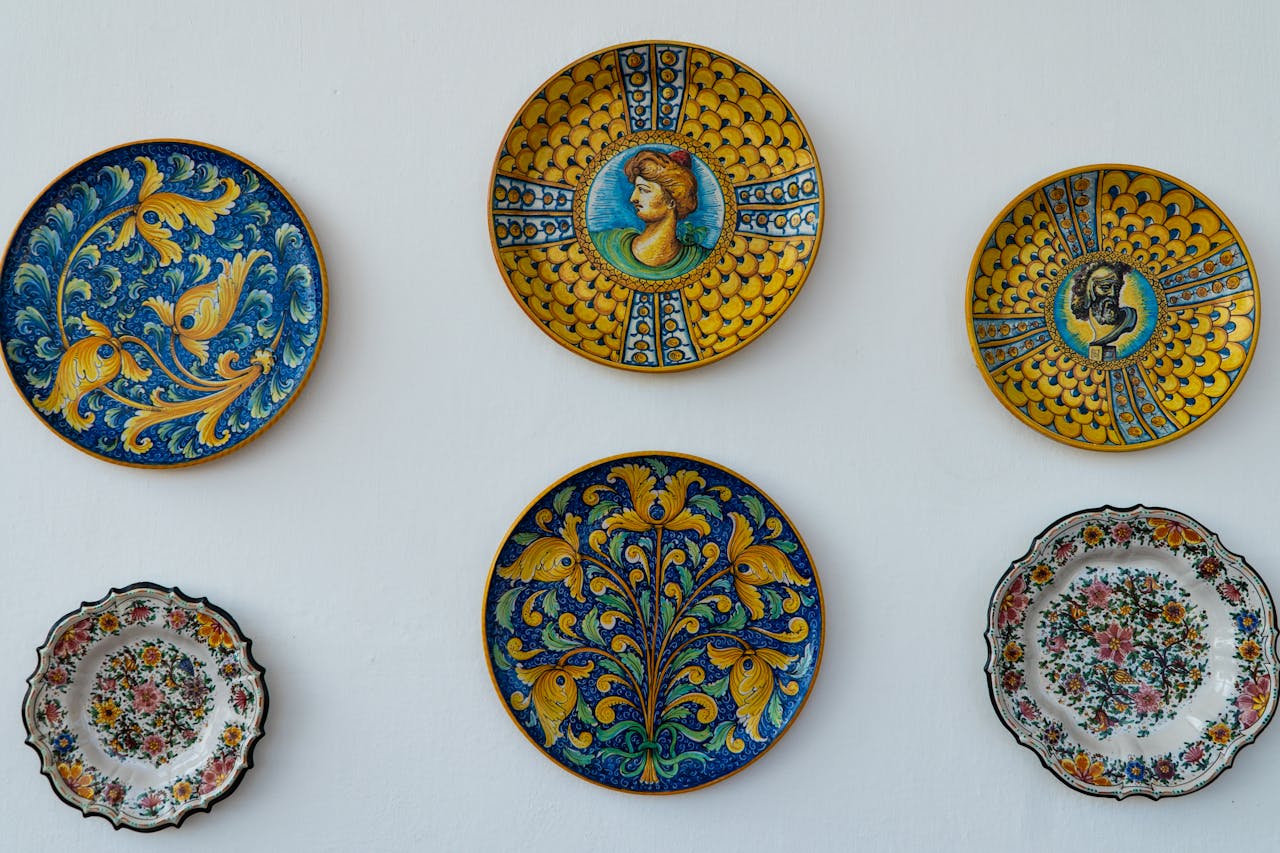 A collection of ornate Italian ceramic plates with vibrant designs and colors displayed on a white wall.